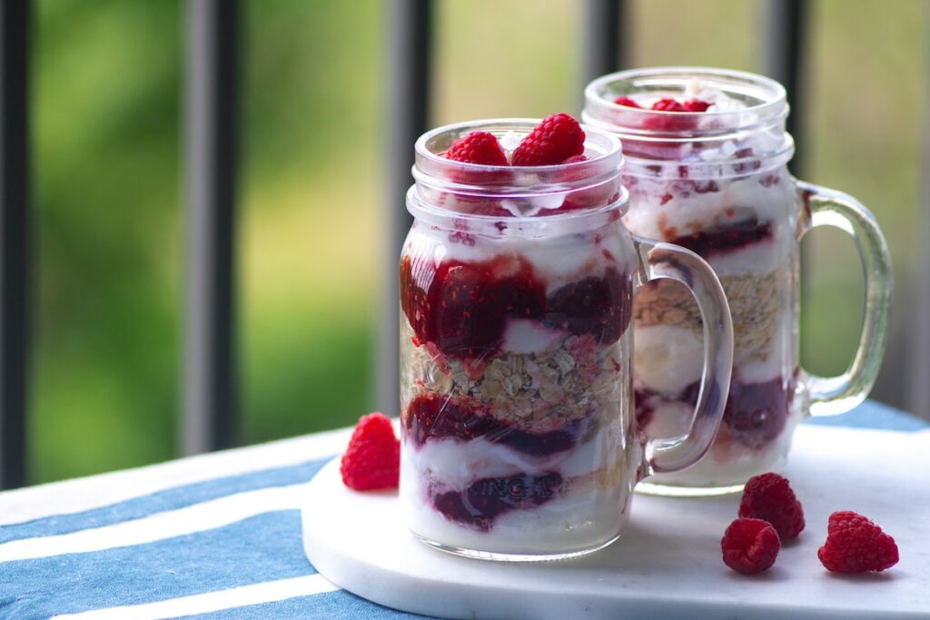 two fruit and yogurt parfaits on an outdoor table; healthy meal prep breakfast recipes concept