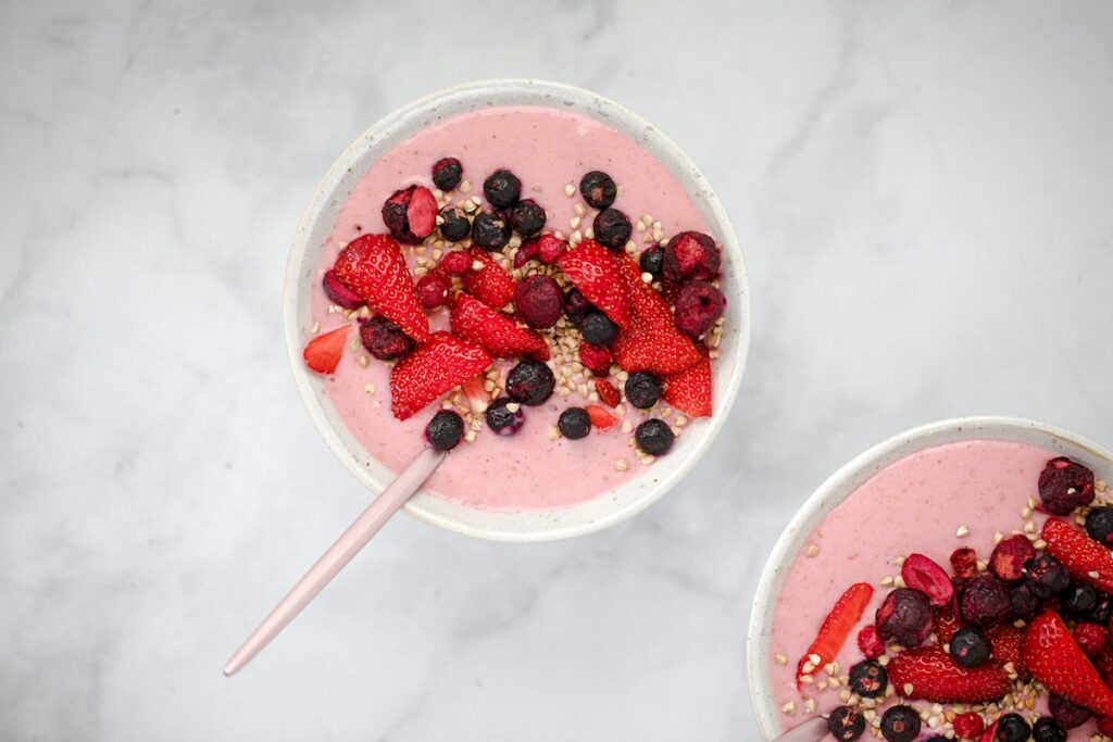 berry smoothies bowls on a white marble counter